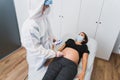 A gynecologist examines a pregnant woman during a Covid 19 pandemic. Fetal doppler heart auscultation. Royalty Free Stock Photo