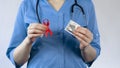 Gynecologist holding red ribbon and condom, AIDS awareness, warning about STI Royalty Free Stock Photo