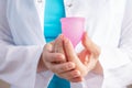 The gynecologist holds a menstrual cup, the doctor recommends a modern eco-friendly hygiene product for use during menstruation