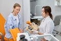 Gynecologist showing bones of female pelvis and giving consultation to woman