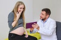 Gynecologist showing echo photo to pregnant woman.