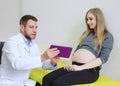 Gynecologist showing echo photo to pregnant woman
