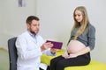 Gynecologist showing echo photo to pregnant woman