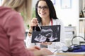 Gynecologist showing patient ultrasound of fetus on tablet