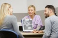 gynecologist showing scan unborn baby to happy couple