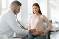 Gynecology consultation. Happy young pregnant woman visiting gynaecologist in maternity clinic, doing medical check-up