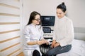 Gynecology consultation, ultrasound concept. Smiling woman doctor showing ultrasound of baby to young happy pregnant Royalty Free Stock Photo