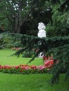 Gypsum bust of a man on a green lawn in a park. Among the beautiful flowers and luxurious green firs.