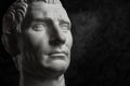 Gypsum copy of ancient statue Augustus head on dark textured background. Plaster sculpture man face. Royalty Free Stock Photo