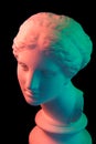 Gypsum copy of ancient statue Venus head isolated on black background. Plaster sculpture woman face. Multi color toned.