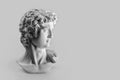 Gypsum statue of David`s head. Michelangelo`s David statue plaster copy on grey background with copyspace for text. Ancient gree