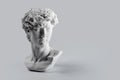 Gypsum statue of David`s head. Michelangelo`s David statue plaster copy on grey background with copyspace for text. Ancient gree