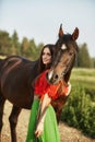 Gypsy girl rides a horse in a field in the summer. A woman with long hair strokes and caresses a horse standing in the green grass Royalty Free Stock Photo