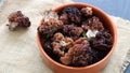 Gyromitra esculenta. conditionally edible mushrooms in a clay bowl, black countertop. spring mushrooms, close-up. Royalty Free Stock Photo