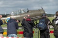 Plane spotters lined up in front of an old propelelr airplane