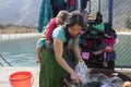 Ha Giang, Vietnam - Feb 7, 2014: Unidentified Hmong very young mother washing clothes at a lake, with the son sleeping on her back