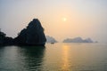 Sunset in Ha Long Bay, Vietnam. Sunset behind misty rock formations, boat in foreground, reflections in South China Sea, Vietnam