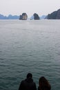 The guy and the girl are sitting together against the backdrop of the cliffs of the Ha Long Bay in Vietnam