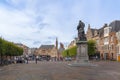 Haarlem/Holland - October 06 2019: People walking and cycling in city center with back, rear view of Statue of Laurens Janszoon