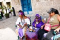 Dark-skinned Cuban in white costume tells fortunes to tourists in Havana streets