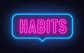 Habits neon neon sign in the speech bubble on brick wall background.