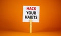 Hack your habits symbol. White paper with words `Hack your habits`, clip on wooden clothespin. Beautiful orange background. Royalty Free Stock Photo