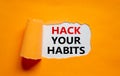 Hack your habits symbol. Words `Hack your habits` appearing behind torn orange paper. Beautiful orange background. Business,