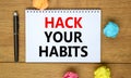 Hack your habits symbol. Words `Hack your habits` on white note on beautiful wooden table, colored paper, black metallic pen.