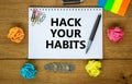 Hack your habits symbol. Words `Hack your habits` on white note. Wooden table, colored paper, paper clips, pen, coins. Business,