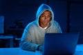 Hacked in and fully focused. a young male hacker using a laptop in the dark.
