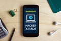 Hacker attack concept on smart phone screen on wooden desk