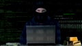 Hacker in balaclava committing cyber crime on laptop, numbers codes background Royalty Free Stock Photo