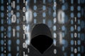 hacker in a black hood at work with graphic background