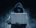 Hacker in black hoodie holding laptop with his hand and binary code Royalty Free Stock Photo