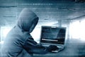 Hacker in black hoodie using laptop on the desk to hacking system with binary code and upload the malware Royalty Free Stock Photo