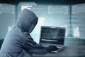 Hacker in black hoodie using laptop on the desk to hacking system with binary code and upload the malware Royalty Free Stock Photo