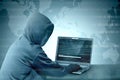 Hacker in black hoodie using laptop on the desk to hacking system with binary code and upload the malware Royalty Free Stock Photo