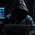 Hacker with black hoodie working on laptop computer