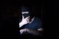 Hacker in black mask with laptop Royalty Free Stock Photo