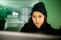 Female young hacker working on computer in dark room programming code Royalty Free Stock Photo