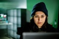 Female young hacker working on computer in dark room programming code Royalty Free Stock Photo