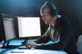 Hacker with computer and headset in dark room