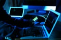 Hacker with credit card and laptop in room, closeup. Cyber crime Royalty Free Stock Photo