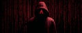 Hacker in dark hooded jacket with red digital code background creating mysterious and intense atmosphere Royalty Free Stock Photo