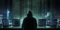 Hacker in dark hoodie using multiple laptops with code on screens