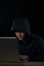 Hacker in a dark hoody sitting in front of a notebook. Computer Royalty Free Stock Photo