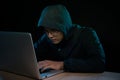 Hacker in a dark hoody sitting in front of a notebook. Computer Royalty Free Stock Photo