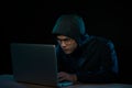 Hacker in a dark hoody sitting in front of a notebook. Computer Royalty Free Stock Photo