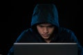 Hacker in a dark hoody sitting in front of a notebook. Computer Royalty Free Stock Photo