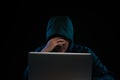 Hacker in a dark hoody sitting in front of a notebook. Computer Royalty Free Stock Photo